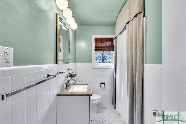 bathroom featuring vanity, toilet, tile patterned flooring, and tile walls