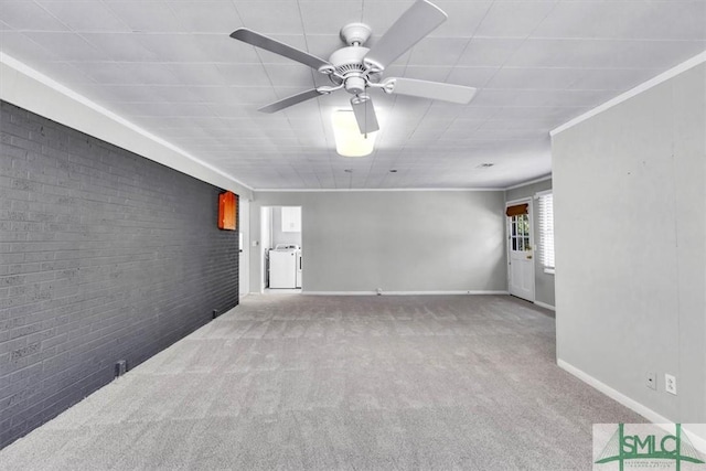 carpeted spare room featuring ceiling fan, brick wall, ornamental molding, and baseboards