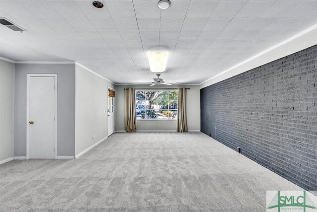 carpeted spare room featuring crown molding and brick wall