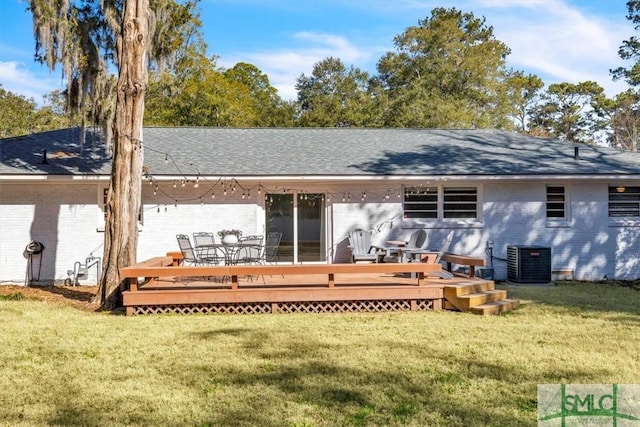 back of property featuring central AC unit, a lawn, outdoor dining space, a wooden deck, and brick siding