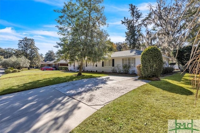 view of front of house featuring driveway, a front lawn, and stucco siding