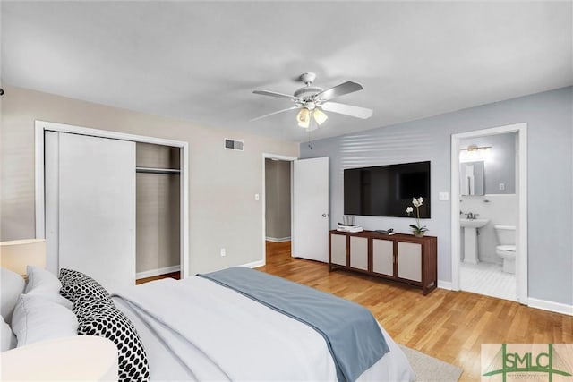 bedroom with a sink, wood finished floors, visible vents, a closet, and ensuite bath