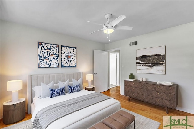 bedroom featuring light wood-style floors, visible vents, and a ceiling fan