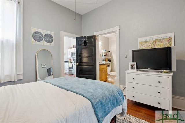 bedroom with connected bathroom and hardwood / wood-style flooring