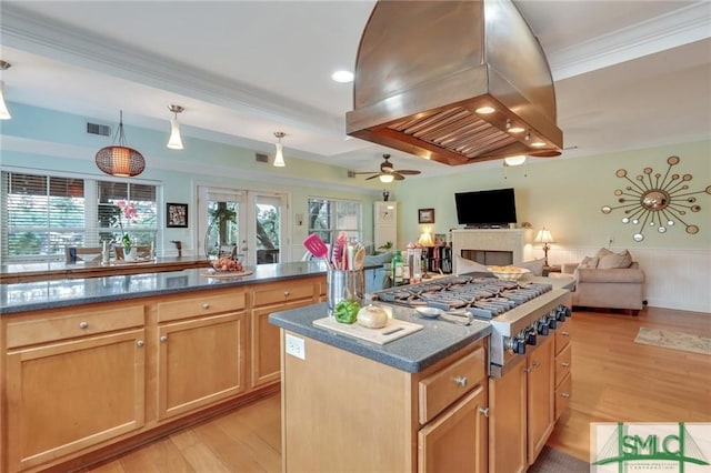 kitchen featuring decorative light fixtures, island exhaust hood, a center island, stainless steel gas cooktop, and light hardwood / wood-style flooring