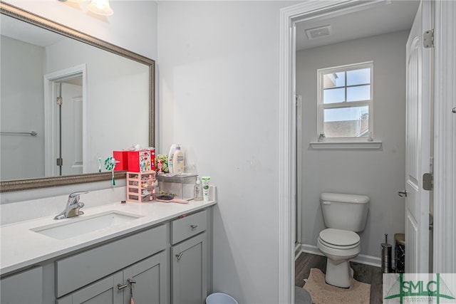 bathroom with walk in shower, vanity, toilet, and hardwood / wood-style floors