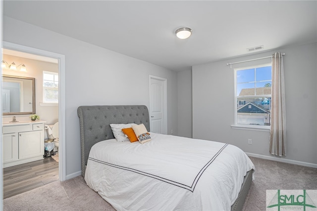 carpeted bedroom with sink and connected bathroom