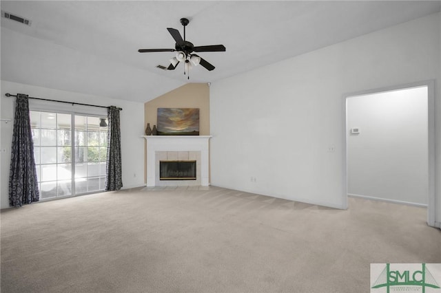 unfurnished living room featuring a tile fireplace, vaulted ceiling, light carpet, and ceiling fan