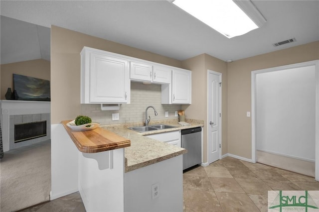 kitchen featuring sink, white cabinetry, a kitchen bar, stainless steel dishwasher, and kitchen peninsula