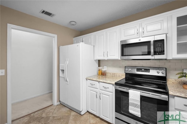 kitchen featuring white cabinetry, light stone counters, light tile patterned floors, stainless steel appliances, and backsplash