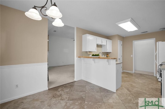 kitchen with decorative light fixtures, white cabinets, a kitchen breakfast bar, white fridge, and kitchen peninsula