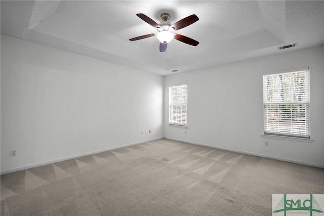 carpeted empty room with ceiling fan, a raised ceiling, and a textured ceiling