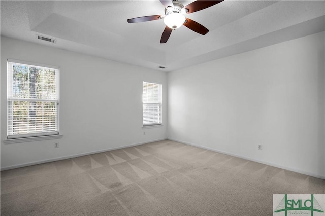 carpeted empty room with a tray ceiling and ceiling fan