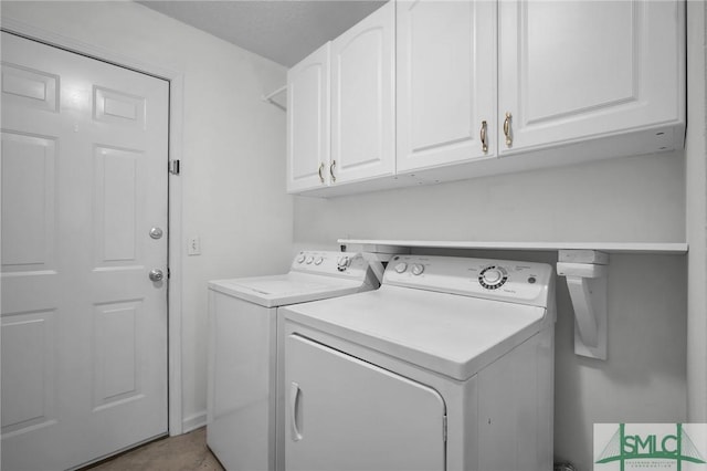 clothes washing area with cabinets and washer and clothes dryer