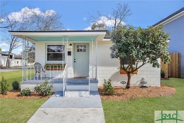 property entrance with concrete block siding, a lawn, and covered porch