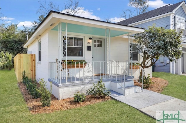 view of front of home with a porch, fence, and a front lawn