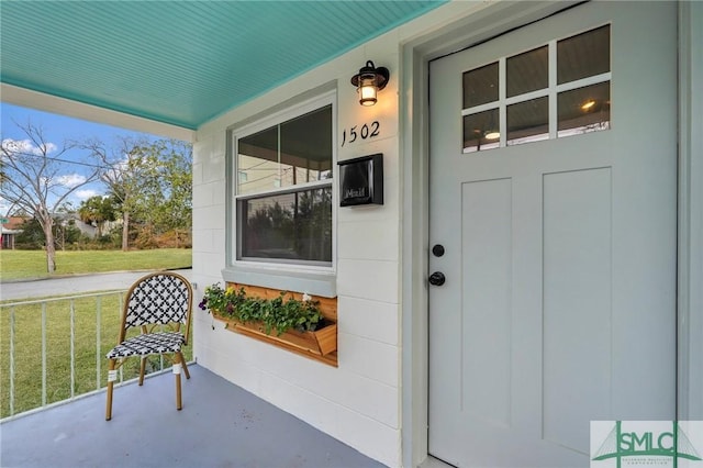 view of exterior entry with covered porch and a lawn