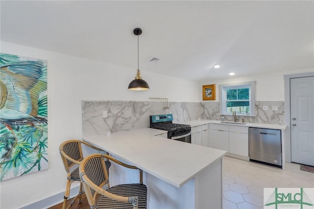 kitchen featuring modern cabinets, a sink, appliances with stainless steel finishes, a peninsula, and white cabinets