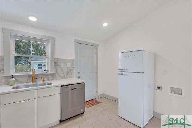 kitchen with a sink, white cabinetry, freestanding refrigerator, light countertops, and dishwasher