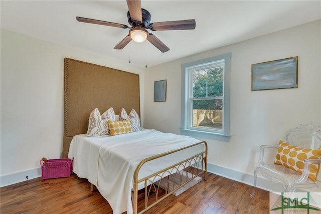 bedroom featuring ceiling fan, baseboards, and wood finished floors