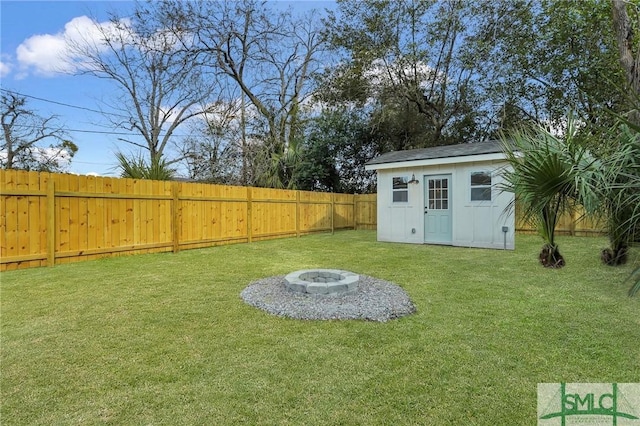 view of yard featuring a storage unit, an outdoor structure, a fenced backyard, and an outdoor fire pit