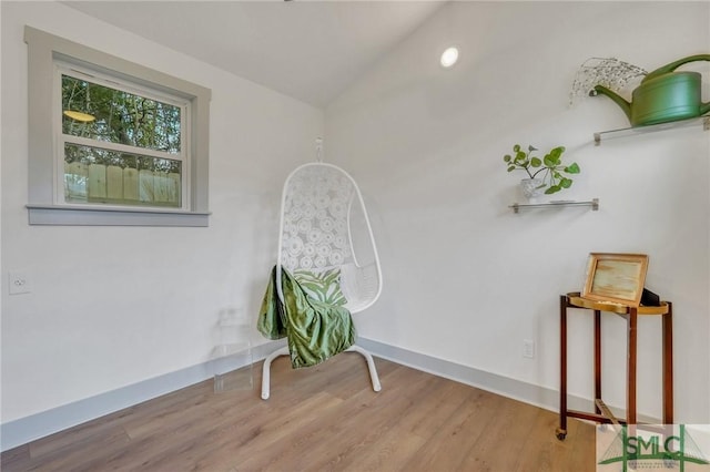 living area with vaulted ceiling, wood finished floors, and baseboards