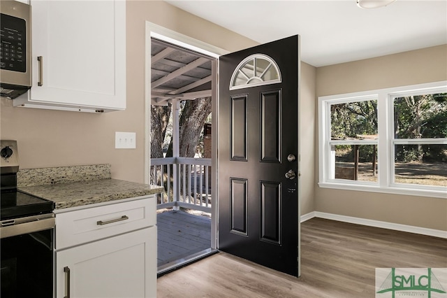 kitchen featuring light stone countertops, light hardwood / wood-style floors, white cabinets, and appliances with stainless steel finishes