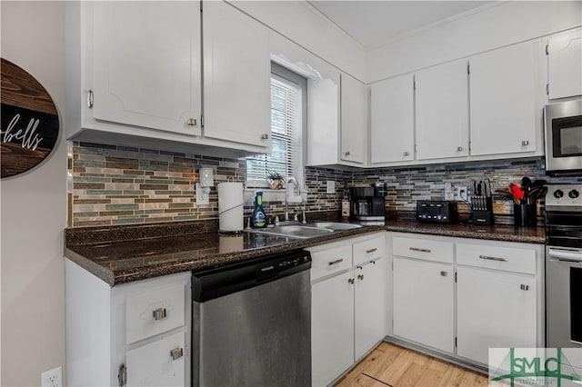 kitchen with sink, light hardwood / wood-style flooring, stainless steel appliances, white cabinets, and decorative backsplash