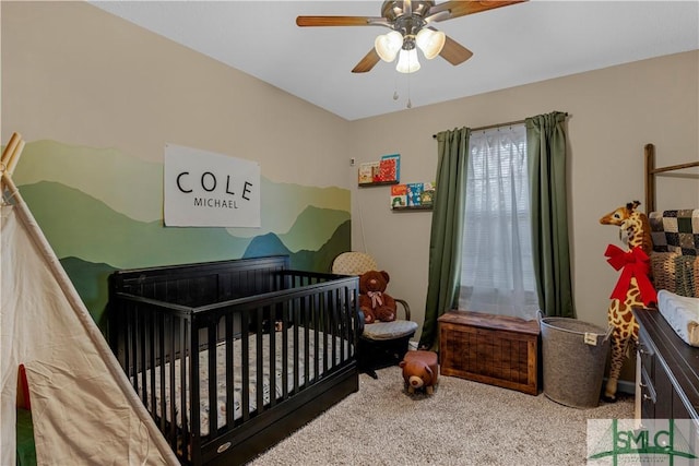 carpeted bedroom featuring a crib and ceiling fan