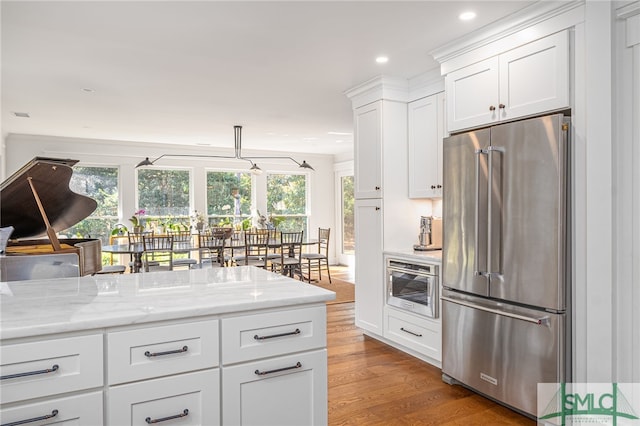 kitchen with white cabinets, high quality fridge, light stone counters, wood finished floors, and recessed lighting