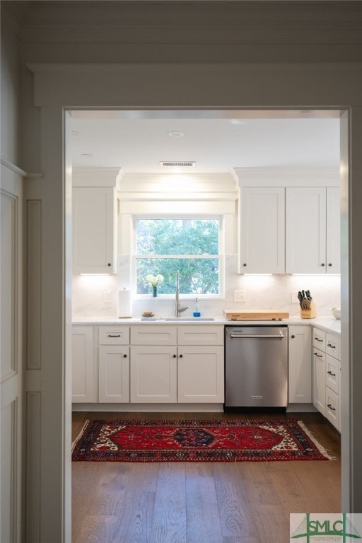 kitchen featuring a sink, visible vents, white cabinetry, stainless steel dishwasher, and wood-type flooring