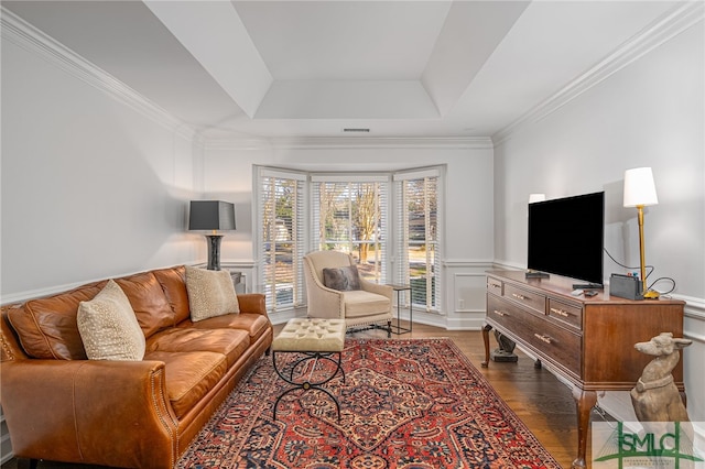 living area featuring wood finished floors, visible vents, wainscoting, a tray ceiling, and crown molding