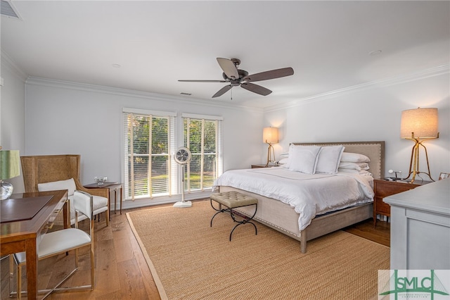 bedroom with light wood finished floors, visible vents, and ornamental molding