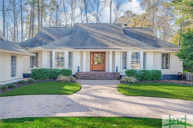 view of front of house with a shingled roof, cooling unit, board and batten siding, and a front lawn