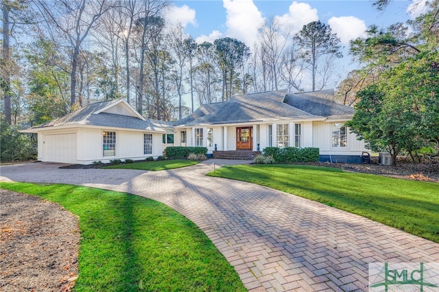 ranch-style house with a garage, cooling unit, a front lawn, and decorative driveway