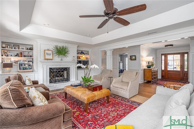 living room featuring ornate columns, built in shelves, visible vents, and a raised ceiling