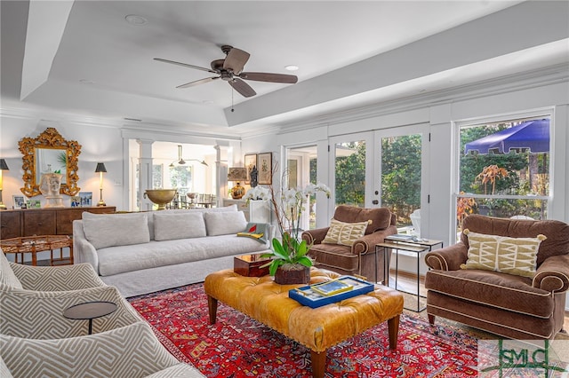 living area featuring crown molding, a raised ceiling, decorative columns, and french doors