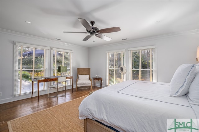 bedroom featuring ornamental molding, wood finished floors, visible vents, and baseboards