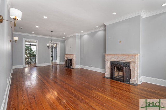 unfurnished living room with hardwood / wood-style flooring, a premium fireplace, an inviting chandelier, and crown molding