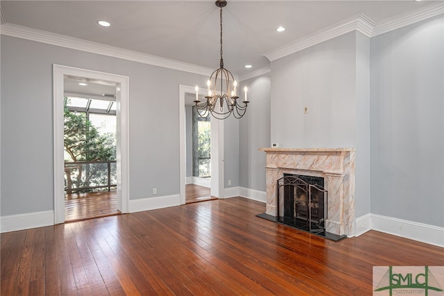 unfurnished living room featuring crown molding, wood-type flooring, a premium fireplace, and a chandelier