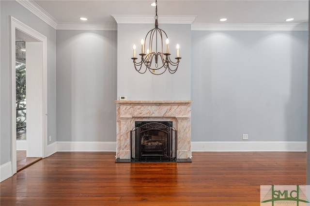 unfurnished living room featuring dark wood-type flooring, ornamental molding, a premium fireplace, and a notable chandelier