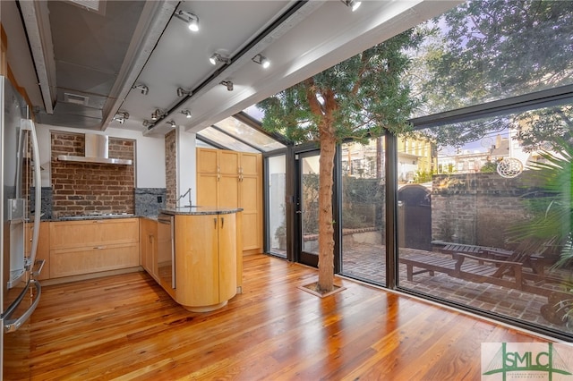 kitchen featuring black cooktop, light brown cabinets, stainless steel fridge, kitchen peninsula, and light hardwood / wood-style floors