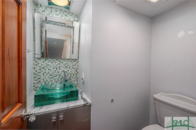 bathroom with toilet, vanity, and decorative backsplash