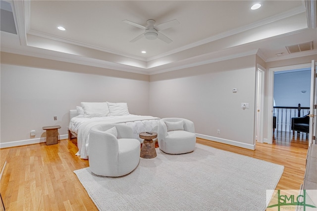 bedroom featuring crown molding, hardwood / wood-style floors, ceiling fan, and a tray ceiling