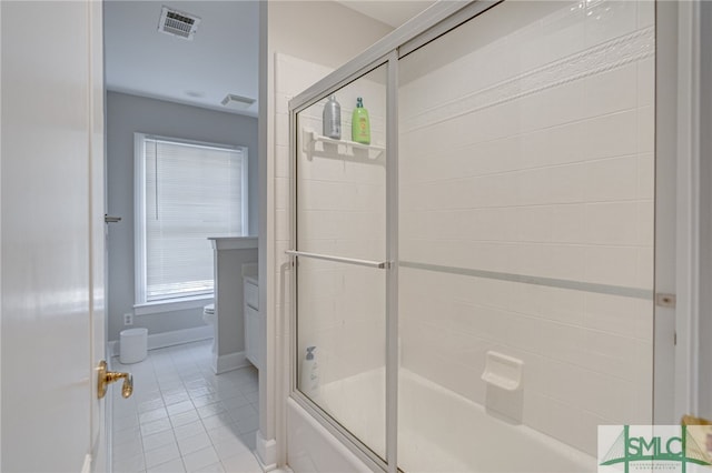 bathroom featuring enclosed tub / shower combo, tile patterned floors, and toilet