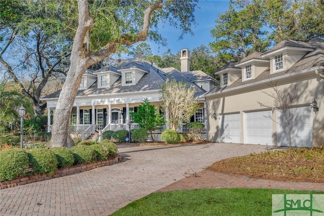 cape cod home featuring a garage and covered porch