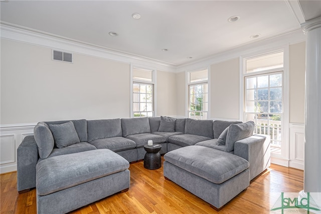 living room featuring ornate columns, ornamental molding, and light hardwood / wood-style floors