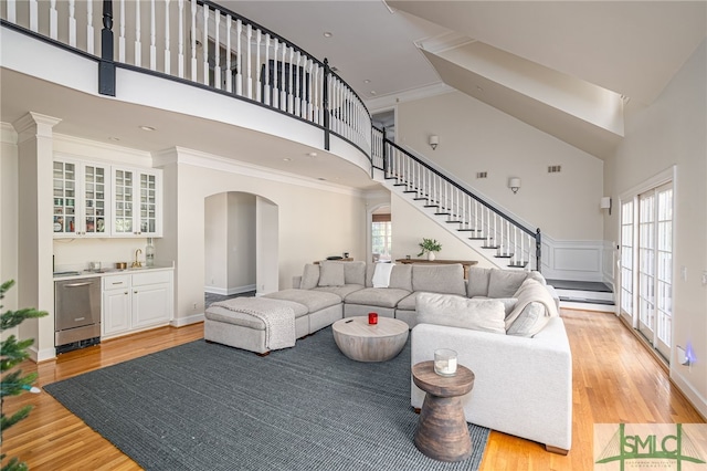 living room featuring a high ceiling, ornamental molding, and light hardwood / wood-style flooring