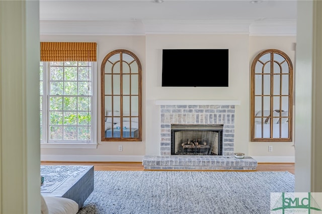 living room featuring crown molding, wood-type flooring, a fireplace, and a wealth of natural light