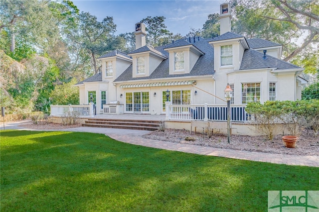 back of house with a deck and a lawn